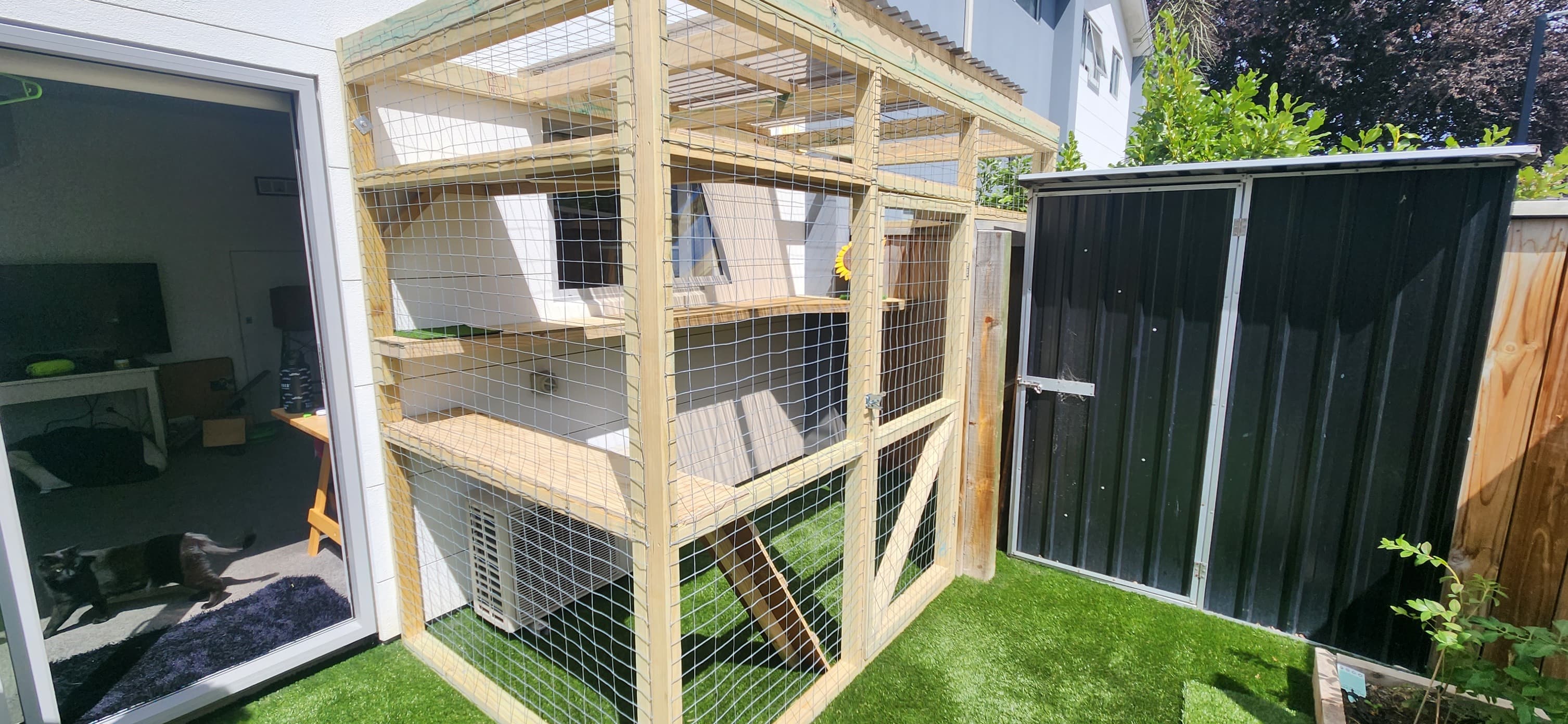 White-framed catio enclosure in a garden