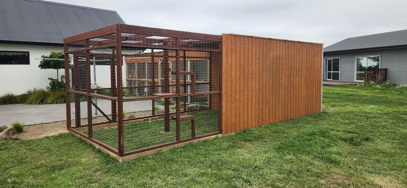 Large timber catio on a lawn with a solid timber wall for wind shelter