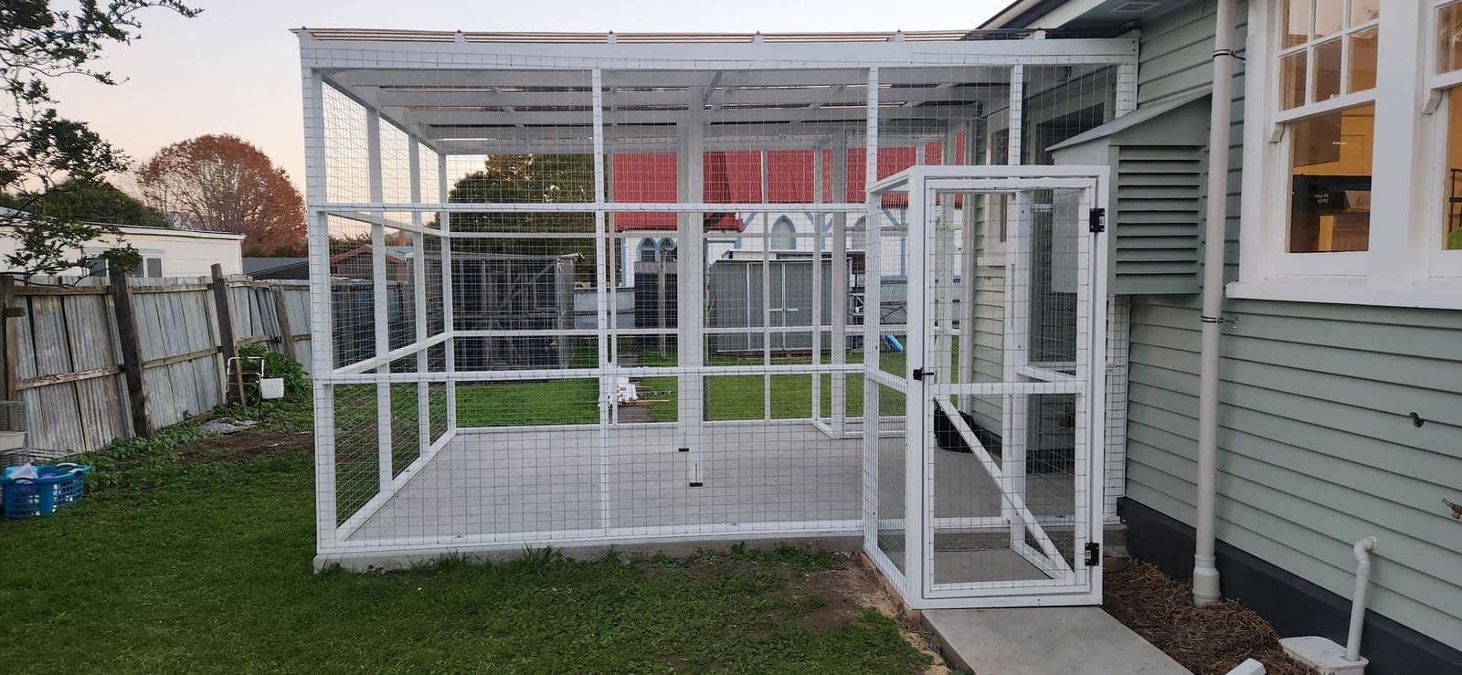 White-framed catio with an open door beside a weatherboard villa